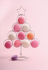 Decorative Christmas tree with sweet macaroons on pink background.