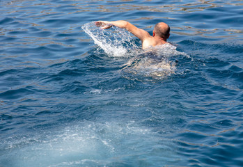 A man swims in the blue water of the sea