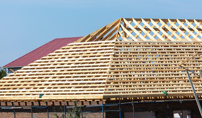 Workers are building the roof of the house from wood