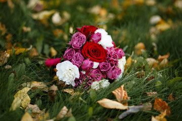 Autumn bouquet of the bride on a background of grass and fallen leaves