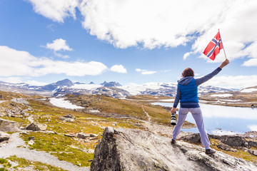 Obraz premium Tourist with camera and flag in Norway mountains