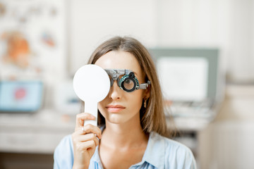Young woman checking vision with eye test glasses during a medical examination at the...