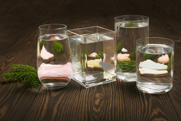 Foods distorted through liquid and glass on dark wooden background.