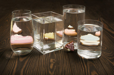 Foods distorted through liquid and glass on dark wooden background.