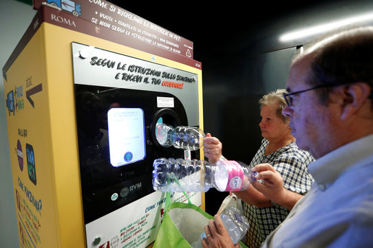 People put plastic bottles into a recycling machine in San Giovanni metro station in Rome