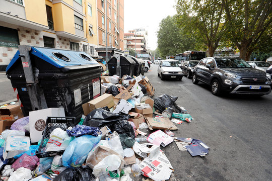 Piles of rubbish lie in front of rubbish bins in Rome