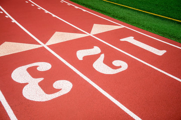 Bright sunny view of athletic running track in fresh red rubber with numbered lanes