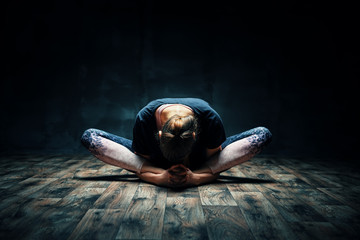Young woman practicing yoga doing reclined goddess pose asana in dark room