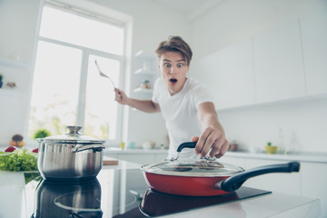 Portrait of his he nice attractive worried scared guy frying spicy meat delicatessen over do timeout recipe at light white modern style interior hotel indoors