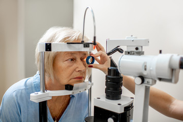 Senior woman during a medical eye examination with microscope in the ophthalmologic office - obrazy, fototapety, plakaty