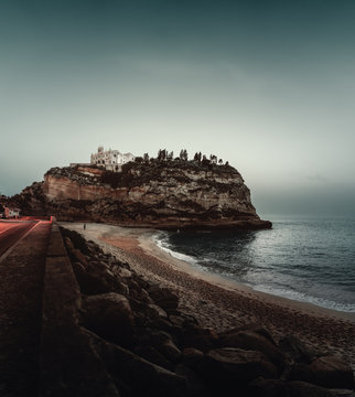 View of beach against Tropea town at dusk