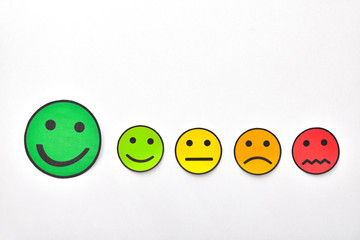 Paper face cutouts on white table highlighting positive rating
