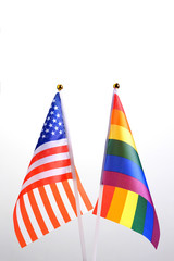 Fototapeta premium USA and LGBT. Two table flags on a white background. The concept of a meeting of American people with representatives of non-traditional sexual orientation. Copyspace.