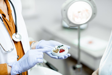 Doctor holding pillbox with some medicine in the gynecological office, close-up view on the hands...