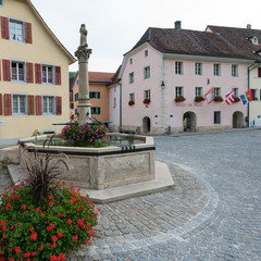 view of the town square with the town hall and fountain in the historic village of Saint-Ursanne