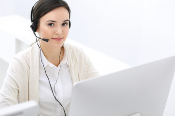 Call center. Beautiful woman receptionist sitting in headset at customer service office. Group of operators at work. Business concept