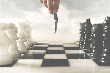 surreal photo of a hand moving a human pawn on a chessboard, a concept of power and control in...
