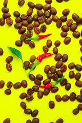 Coffee beans and red peppers on yellow background