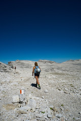 female mountain climber hikes across a wild rock desert high in the Dolomites after a hard climb