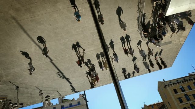 crowd filmed in reflexion on a metal mirror ceiling in the city of Marseille France