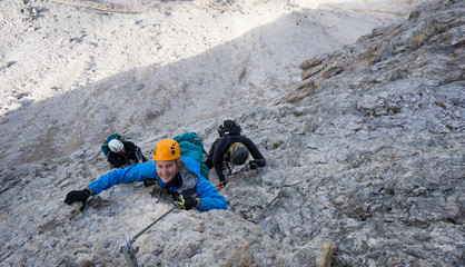 mountain climbers on a steep and exposed rock face climbing a Via Ferrata