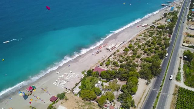 Top view of city beach with beautiful blue ocean water. Stock footage. Highway runs along coast near beach and blue waters of ocean. Great place for summer holiday on ocean