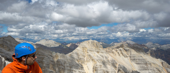 young male mountain climber on a Dolomite mountain peak enjoying the view