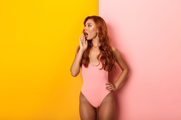 Photo of shocked ginger woman wearing pink swimsuit looking aside at copyspace