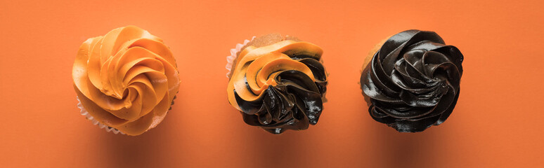 top view of delicious Halloween cupcakes on orange background, panoramic shot