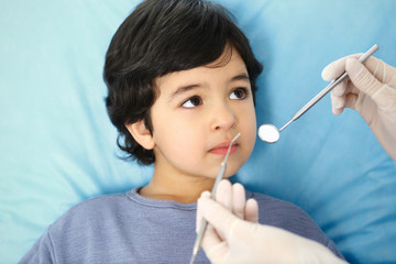 Little arab boy sitting at dental chair with open mouth during oral check up while doctor. Visiting...