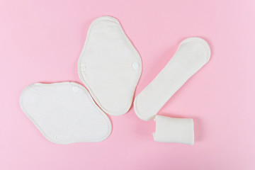 Reusable eco-friendly female pads made of natural fabric with fleece coating for every day. Pink background, place for text, minimalism, top view, flat lay. Zero waste concept