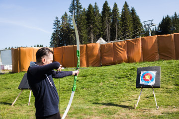 Man with bow and arrow practicing archery outdoors.