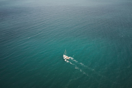 Aerial view of a white boat sailing in the blue sea. Water transportation and summer leisure time activity. © VAKSMANV