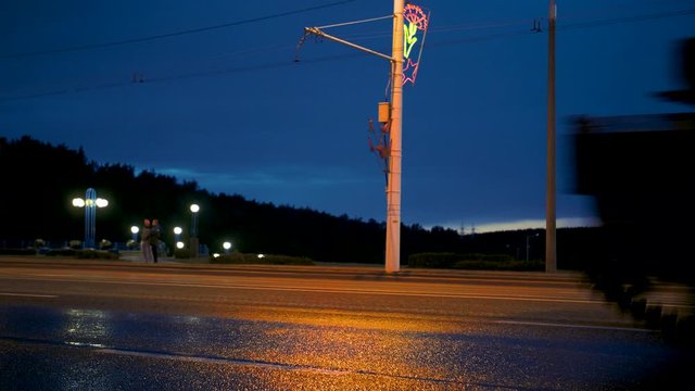 A convoy of military equipment rides through the city at night with headlights on