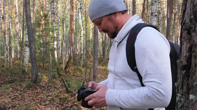 man holds a camera, photographing the autumn nature against the background of a yellowed park.