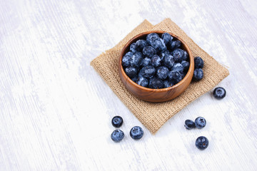 Fresh blueberries in a wooden bowl on burlap