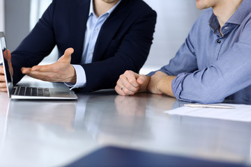 Business people using laptop computer while working together at the desk in modern office. Unknown businessman or male entrepreneur with colleague at workplace. Teamwork and partnership concept