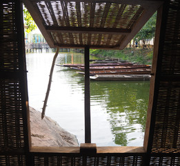 View from the wooden window that can see the wooden boats in the pond.
