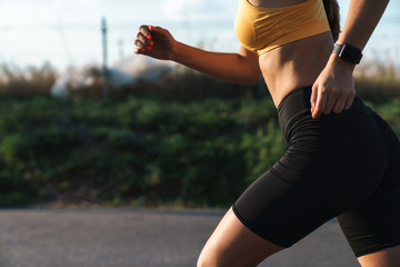 Cropped image strong of young woman in sportswear running outdoors