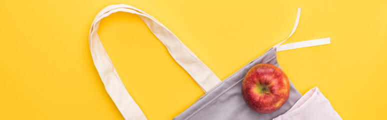 top view of ripe apple on eco friendly bags isolated on yellow, panoramic shot
