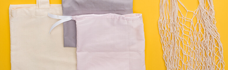 top view of cotton eco friendly bags isolated on yellow, panoramic shot