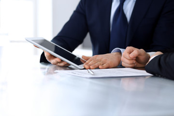 Business people using tablet computer while working together at the desk in modern office. Unknown businessman or male entrepreneur with colleague at workplace. Teamwork and partnership concept