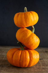 Orange littlep pumpkins on dark wooden background deep shadows, rustic style halloween, thanksgiving, autumn