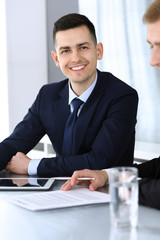 Businessmen or partners working together while using tablet computer at the desk in modern office. Headshot of male entrepreneur or manager with colleague at workplace. Teamwork, partnership and