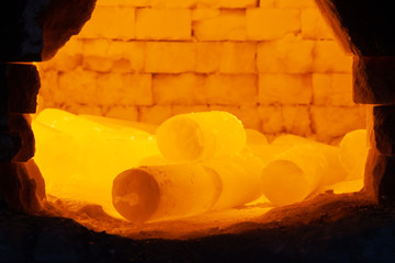 red-hot steel metal billets are heated in a furnace before forging by a blacksmith in a forge