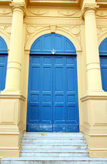 Close â€“ up Old textured door.The green wood door with White wall. A Window  with Frame They are in Thailand.