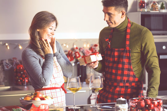 Netter Mann, der seine Freundin mit Weihnachtsgeschenk in der K&uuml;che &uuml;berrascht