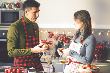 Netter Mann, der seine Freundin mit Weihnachtsgeschenk in der Küche überrascht