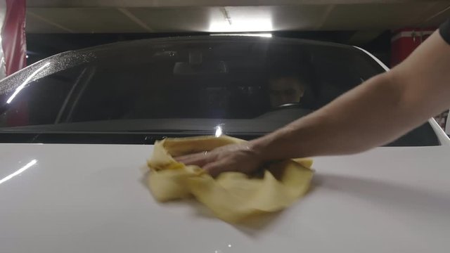 Hand of auto mechanic that polishes car bonnet with wiper