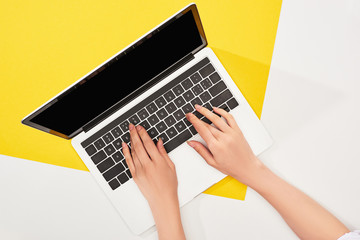 cropped view of woman using laptop on yellow and white background